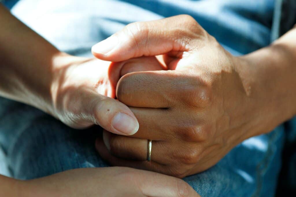 A close-up image of a healthcare provider's hand holding a patient's hand