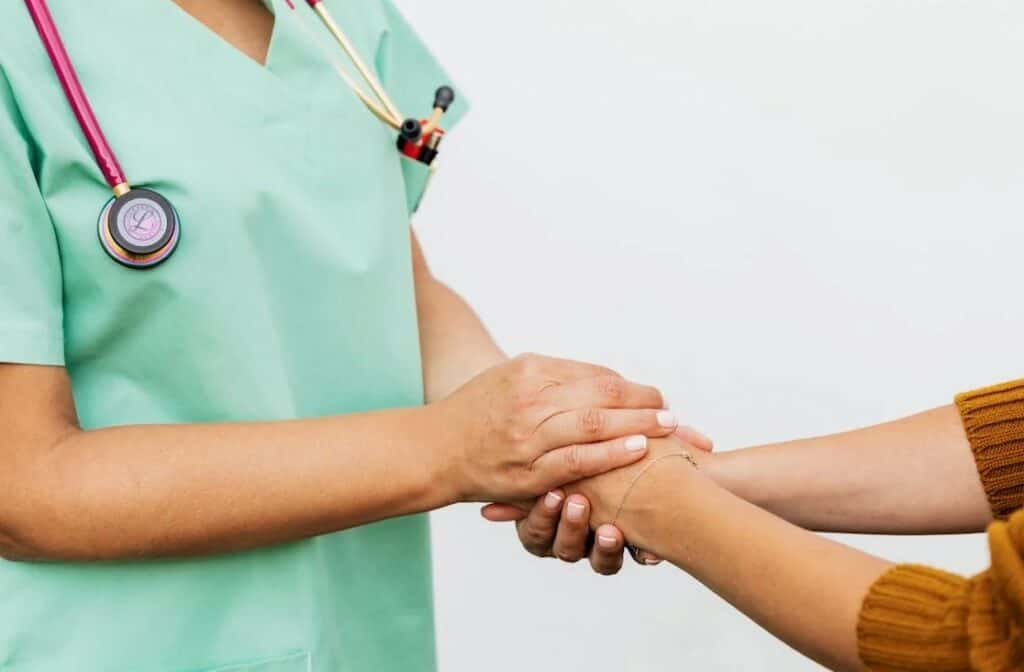 A doctor in green scrubs and a patient shake hands to illustrate patient-centered communication tools and strategies.